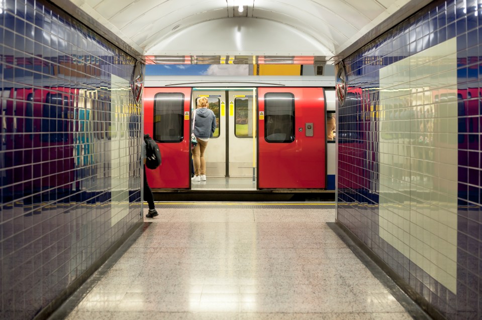 A London Underground train at a station platform with its doors open.