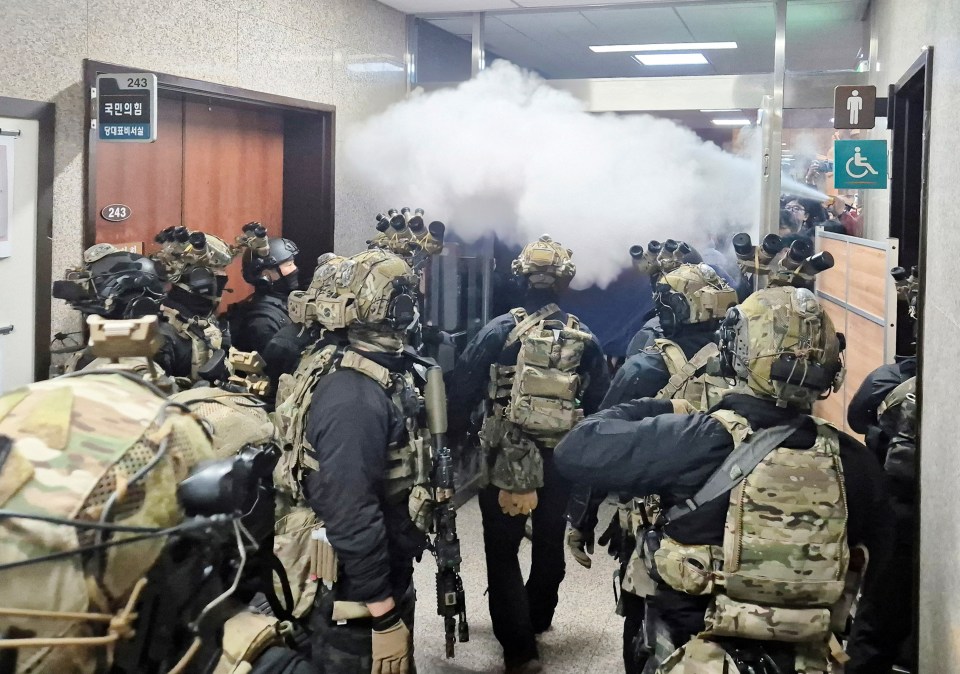 Soldiers in tactical gear entering a building, smoke billowing.