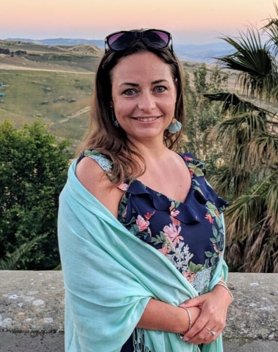 Woman in floral dress and mint shawl, outdoors at sunset.