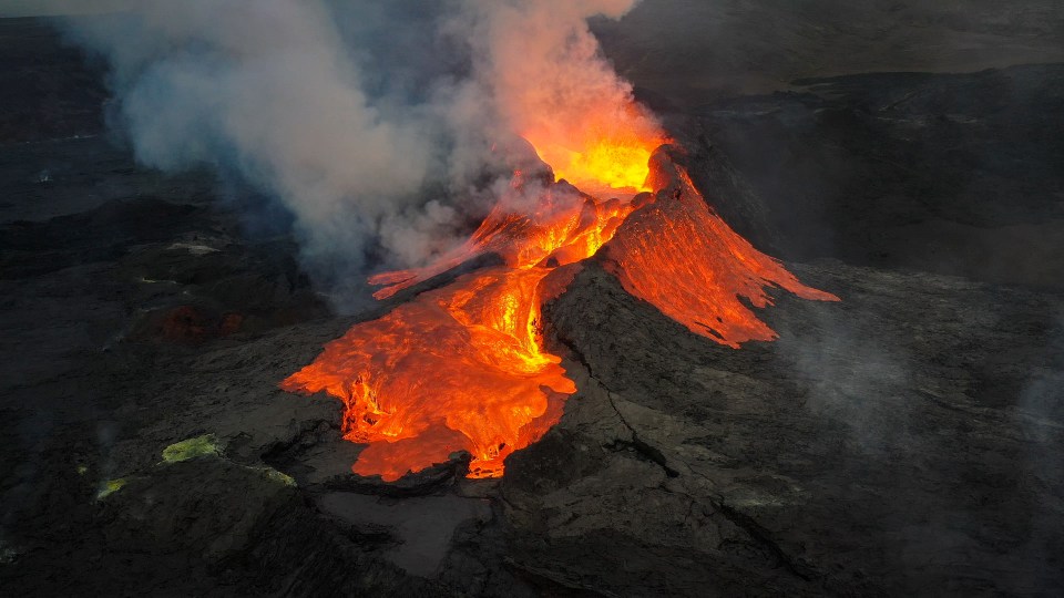 Aerial view of a volcano erupting at night.