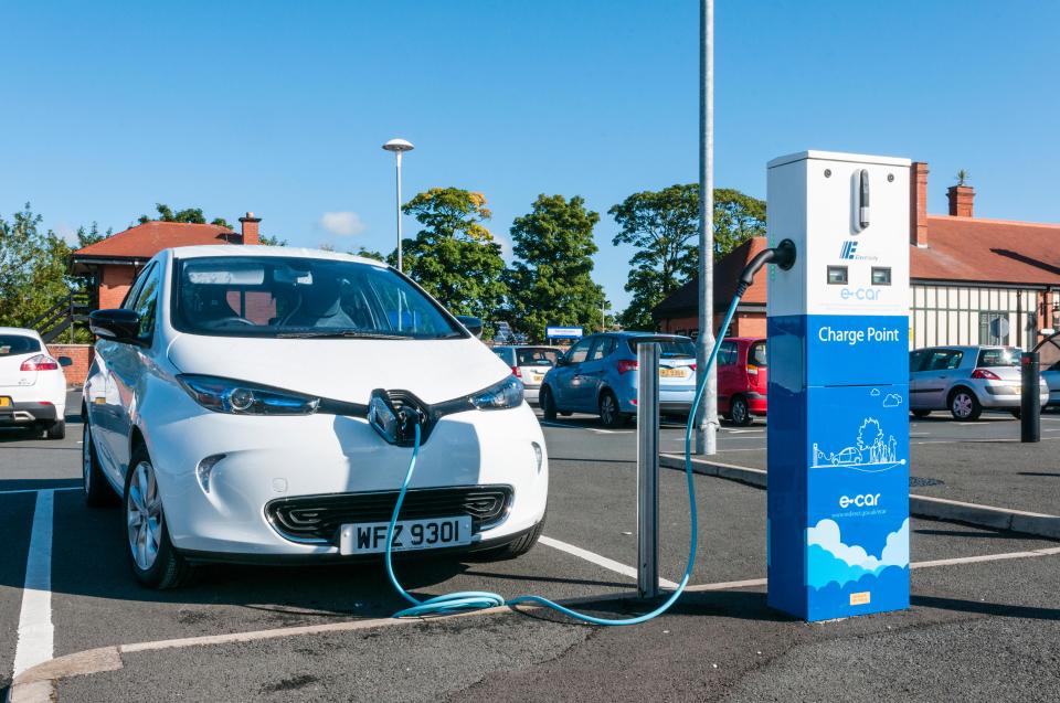 White electric car charging at a station.