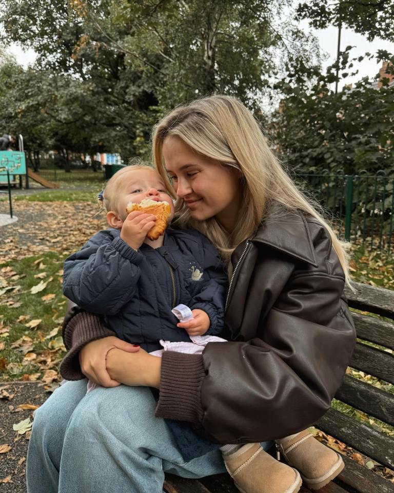 Woman and toddler sharing a pastry on a park bench.