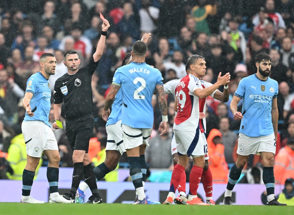 Referee showing Leandro Trossard a red card during a soccer match.