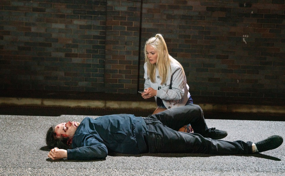 A woman looks down at an injured man lying on the ground.