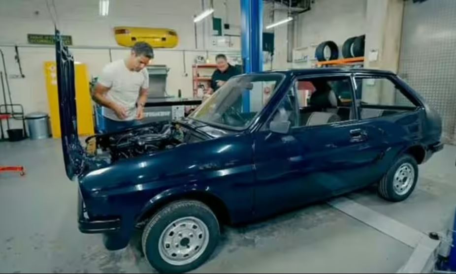 Mike Brewer working on a dark blue Ford Fiesta.