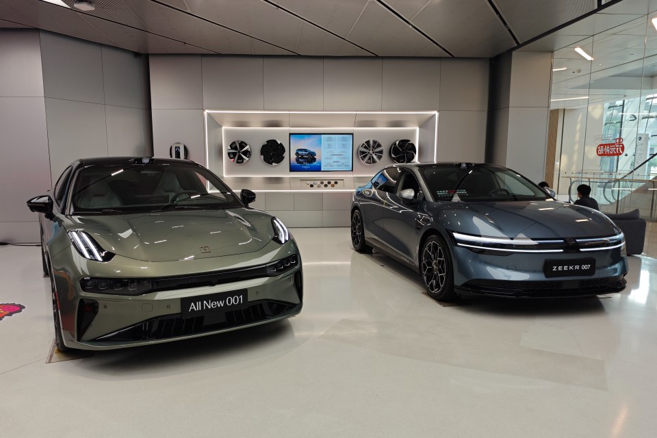 Two electric vehicles, a green Zeekr 001 and a blue Zeekr 007, on display in a showroom.