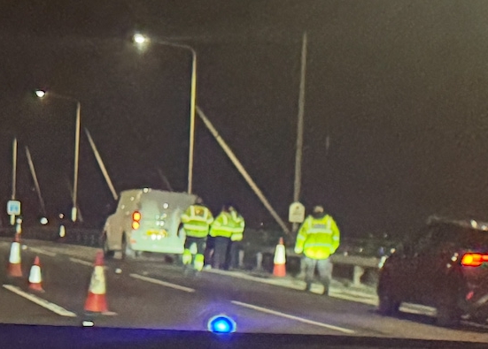 Nighttime photo of a crime scene investigation on a bridge.