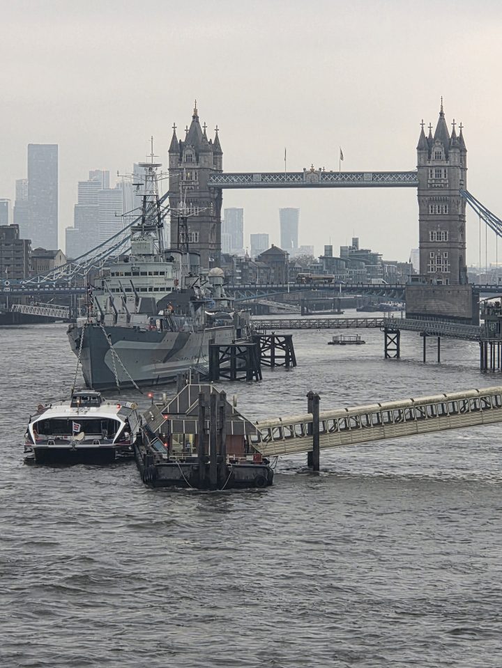 A warship moored on the Thames, with Tower Bridge in the background.