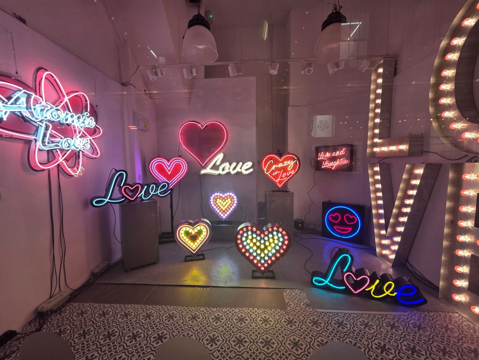 Neon signs in various shapes and colors spelling out "love".