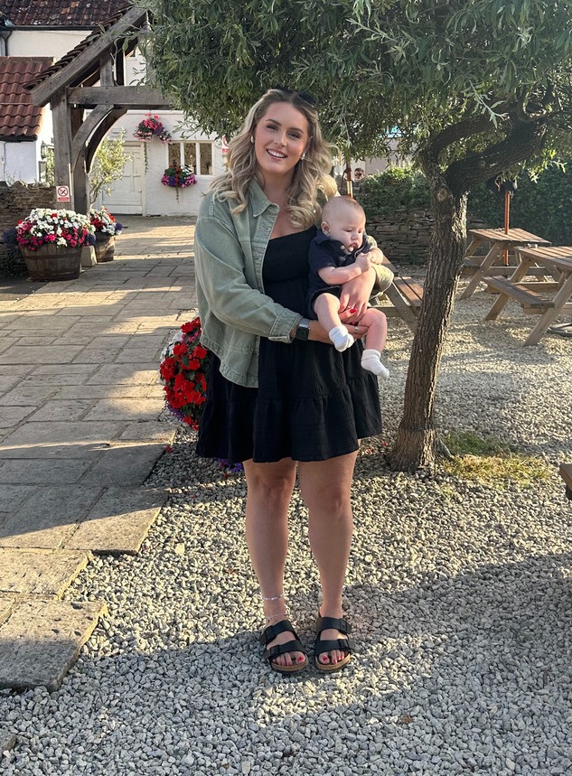 Woman holding a baby in a pub garden.