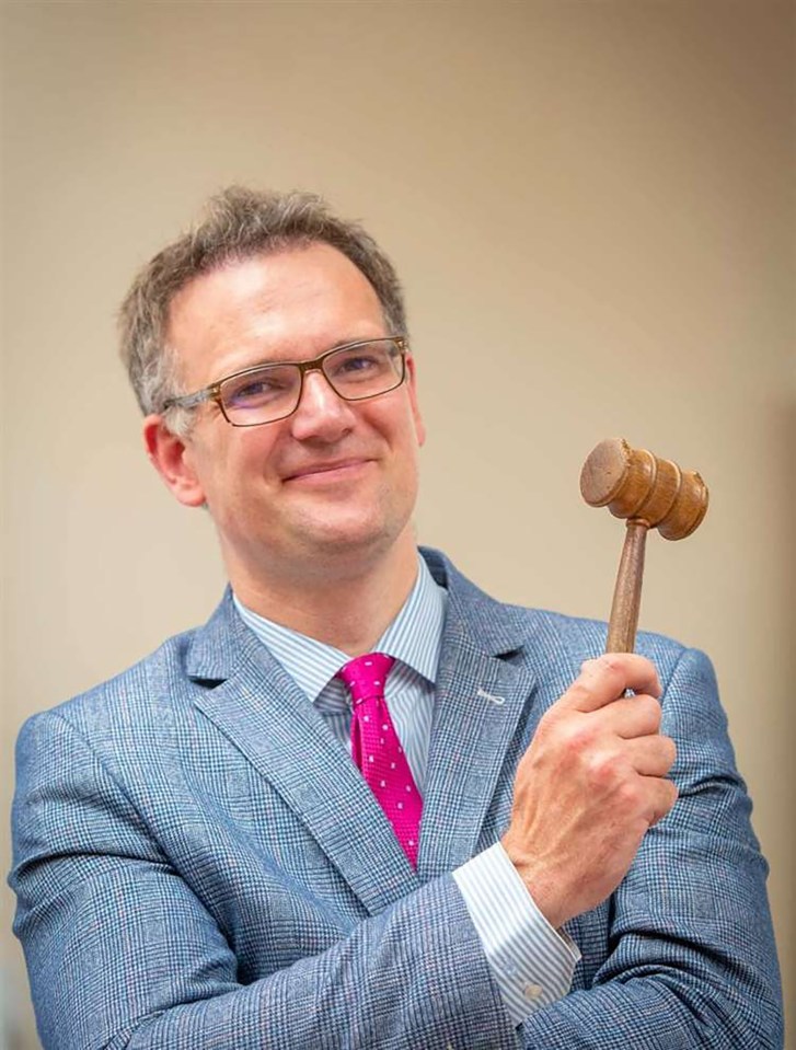 Portrait of Charles Hanson, owner of Hansons Auctioneers, holding an auction gavel.