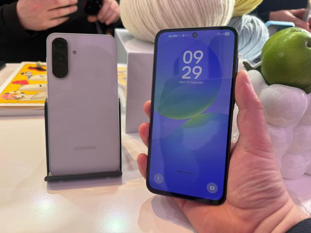 A lavender Samsung phone displayed next to a black phone in a hand.