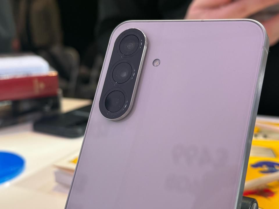 Close-up of a lavender smartphone's triple-lens camera.