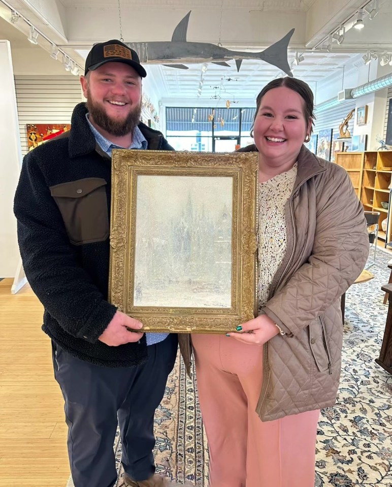 Couple holding a framed painting.