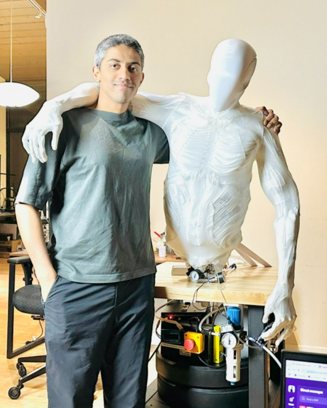 A man standing with his arm around a faceless humanoid robot.