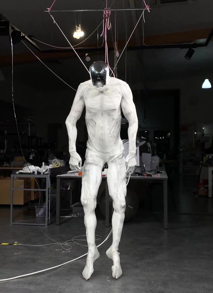 A white humanoid robot suspended from the ceiling.