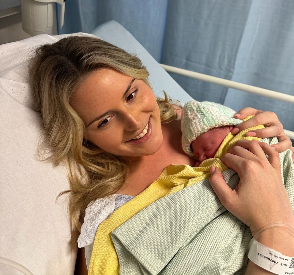 A mother holding her newborn baby in a hospital bed.