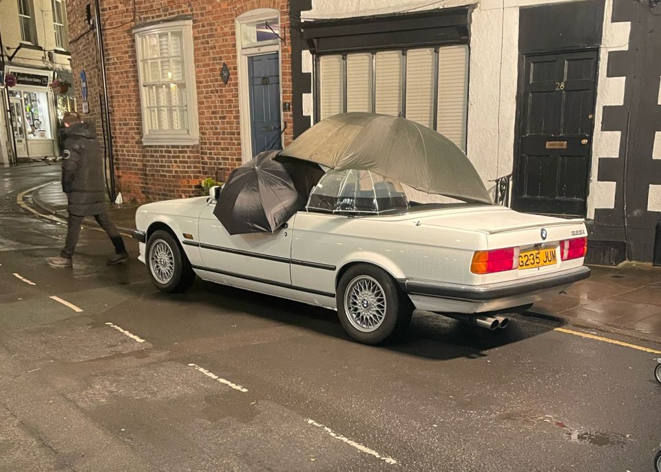 A white BMW convertible with umbrellas on it during filming.