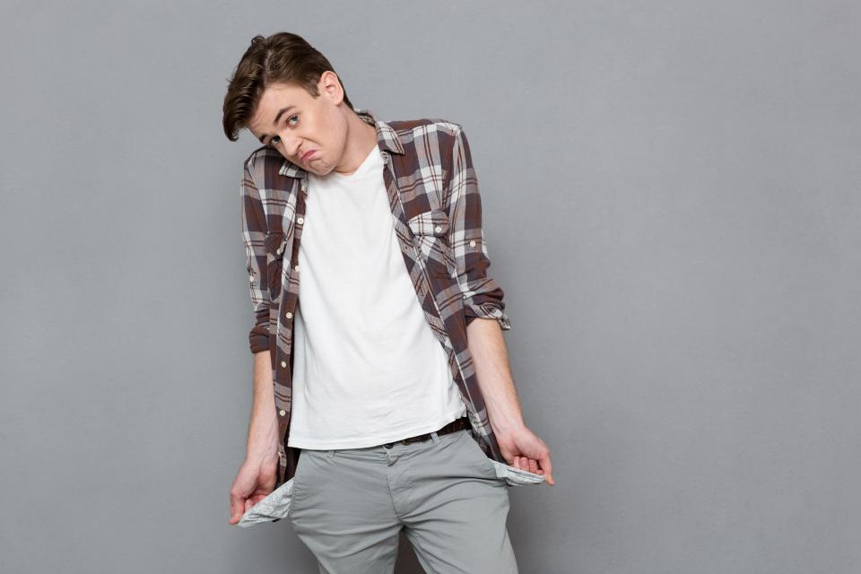 Young man showing empty pockets.