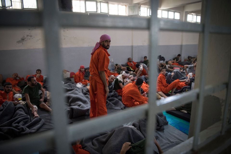 Men accused of being affiliated with ISIS sit on the floor of a Syrian prison.