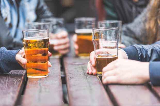 Close-up of hands holding glasses of beer at a pub table.