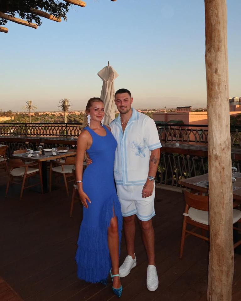 Couple posing on a patio overlooking a city.