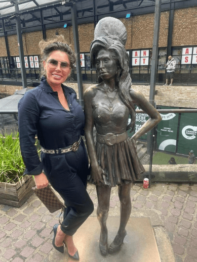 Woman standing next to Amy Winehouse statue.