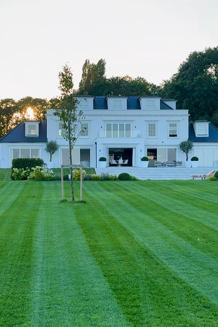 Large white house with manicured lawn.