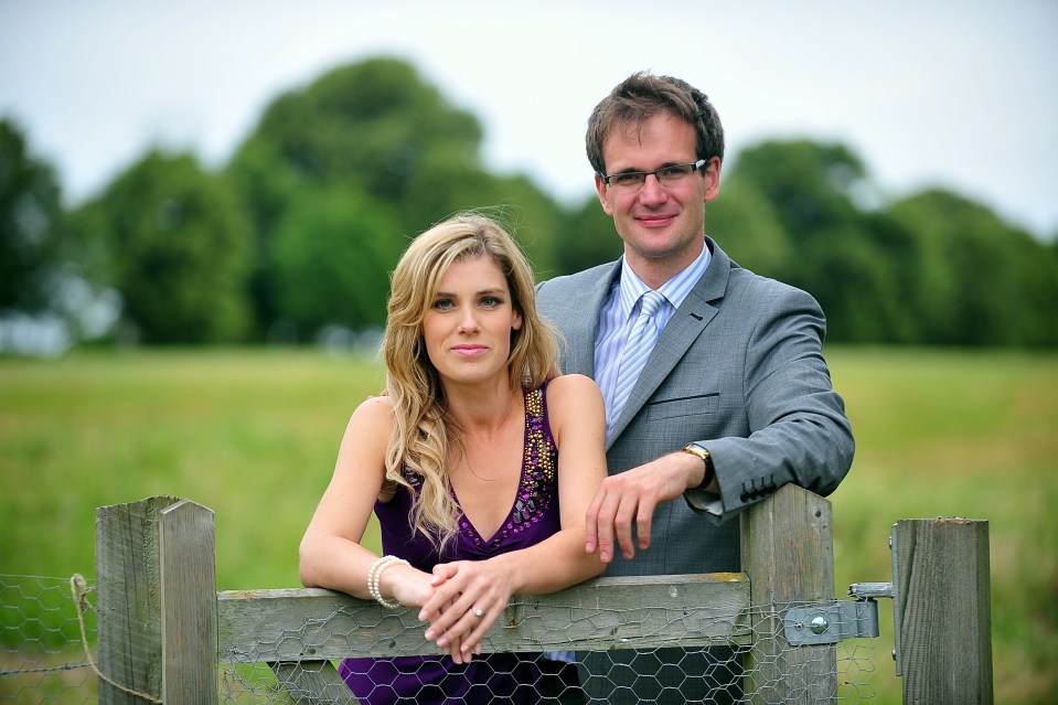 Couple posing by a fence.