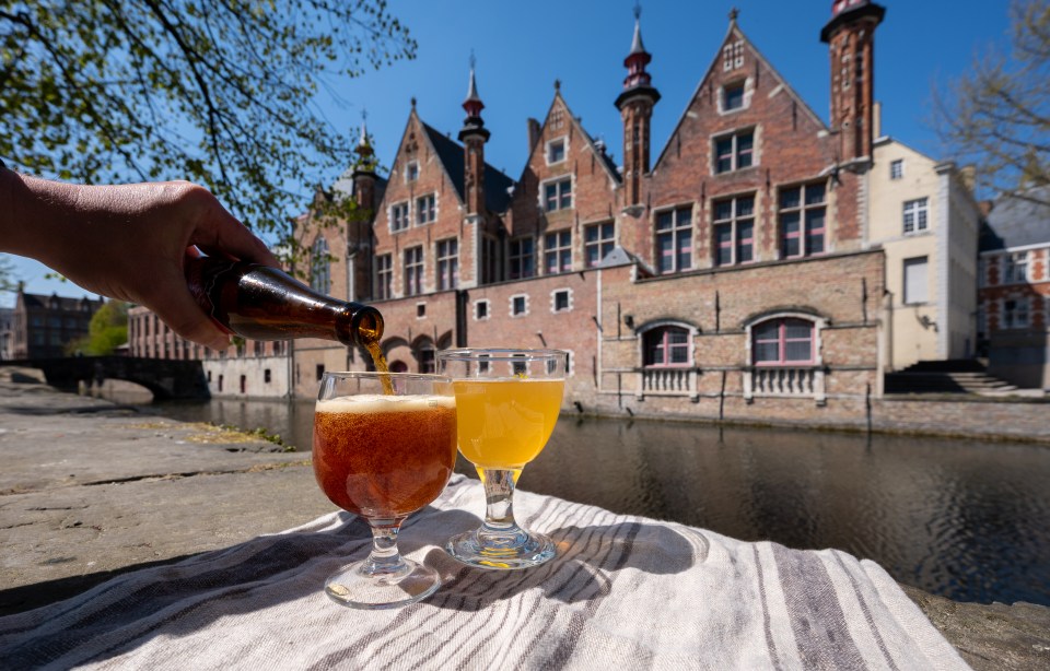 Belgian beer being poured into a glass on a canal-side patio in Bruges.