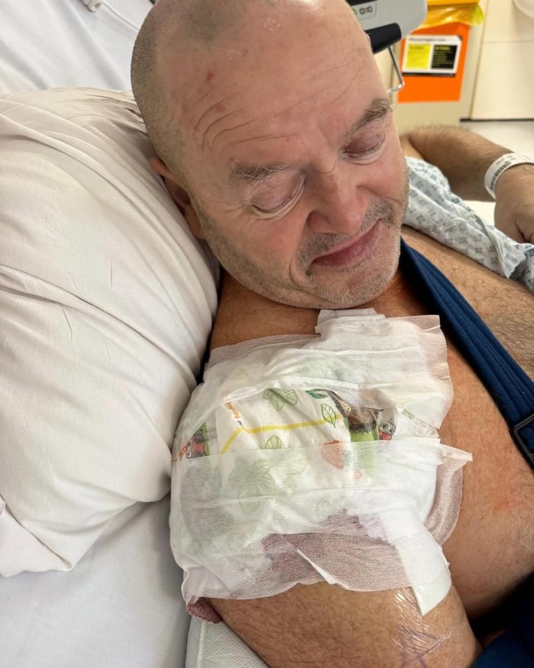 Man in hospital bed with bandaged shoulder.