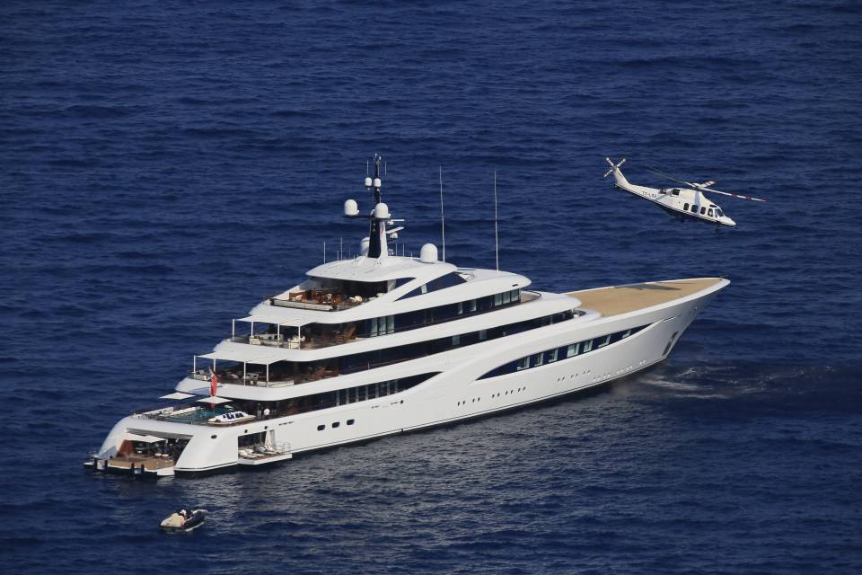 Aerial view of a large yacht and helicopter at sea.
