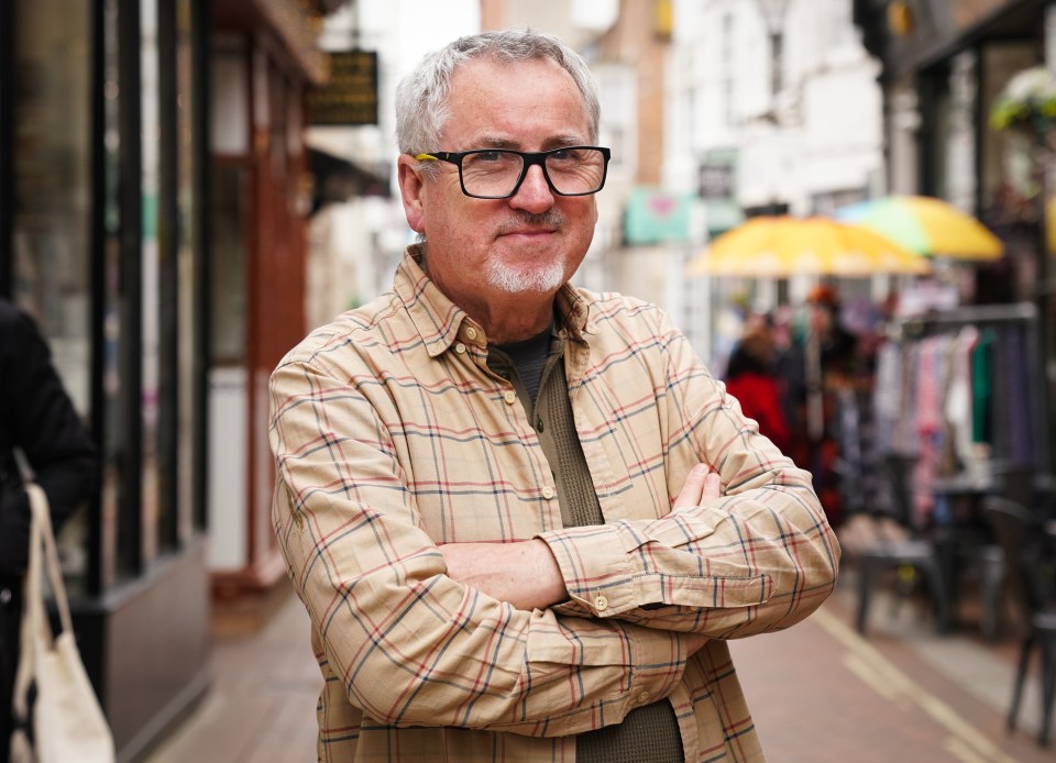 Portrait of a man with arms crossed standing on a street.