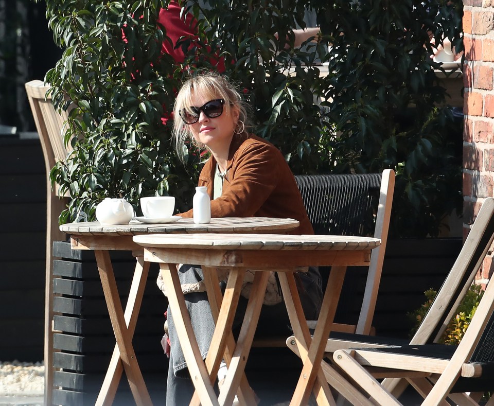 Woman sitting at a cafe table without her wedding ring.