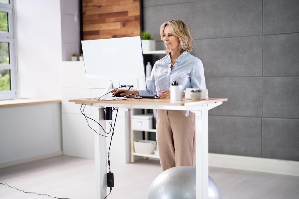 Woman working at an adjustable height standing desk in an office.