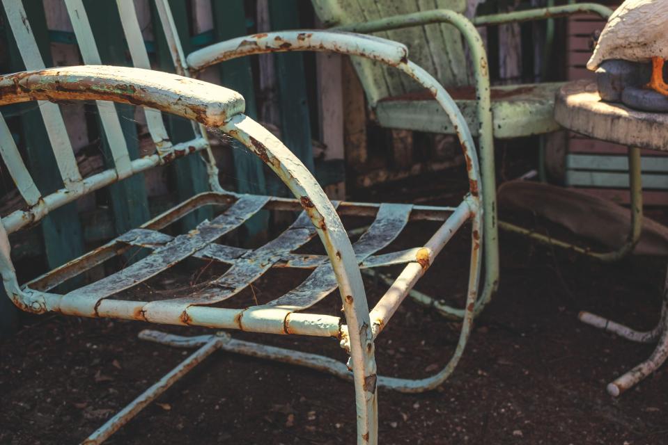Rusty metal patio chairs in a backyard.