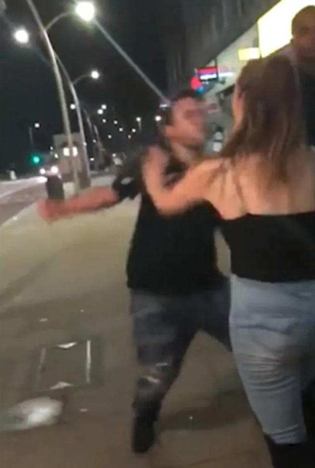 Man punching woman on street at night.