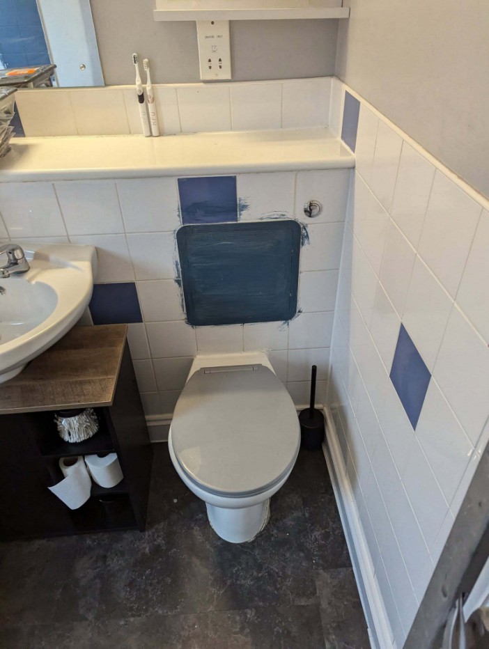 Bathroom under renovation with painted tiles and toilet.