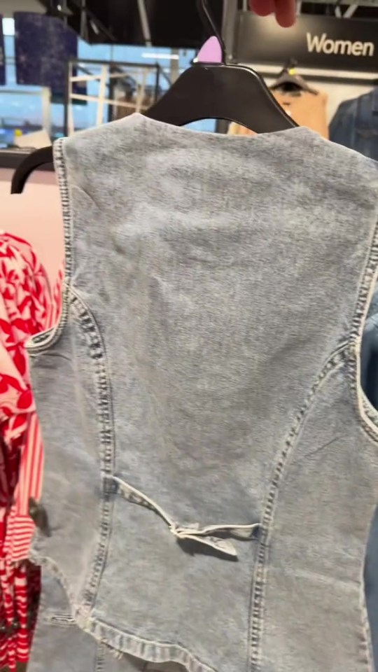 Light blue denim vest on a hanger.