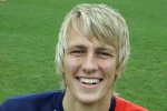 Smiling young man in a red soccer jersey.