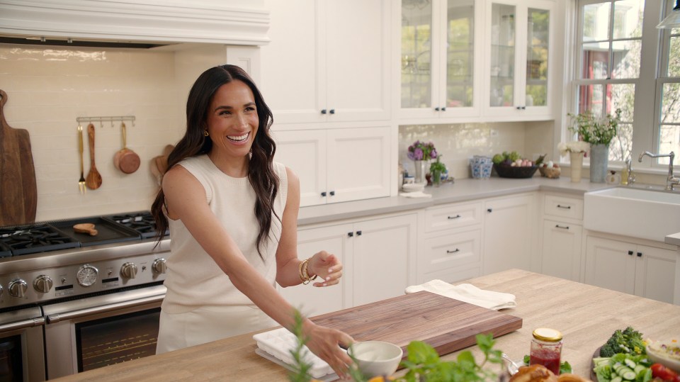 Meghan Markle in a kitchen, smiling.