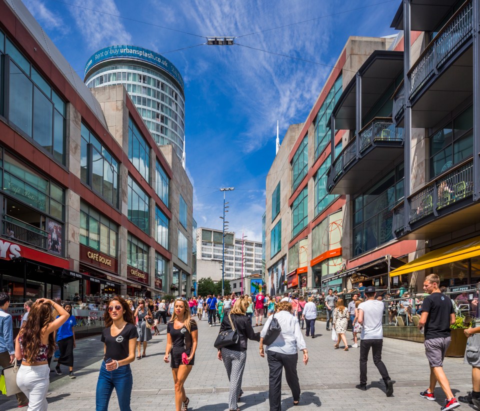 People walking on a city street with shops and buildings.
