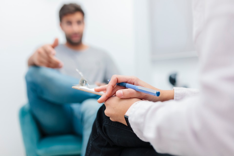 A therapist taking notes while listening to a patient.