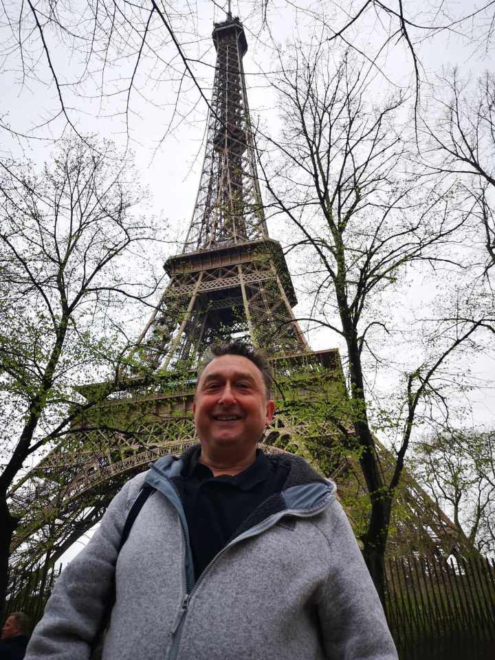 Man smiling in front of the Eiffel Tower.