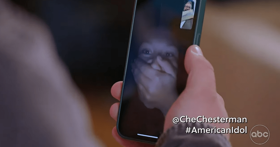Screenshot of a person on a video call, covering their mouth with their hand.  A smaller video of another person is visible on the screen.  The text "@CheChesterman #AmericanIdol" and the ABC logo are visible.
