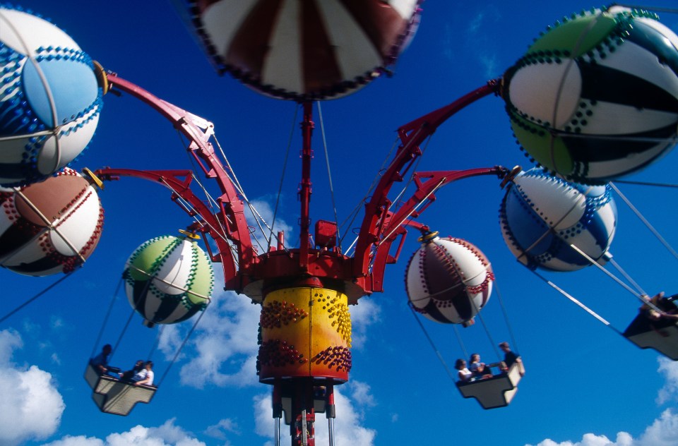 Fairground ride with colorful balloon-shaped gondolas against a blue sky.