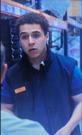 A young man wearing a blue vest and name tag.