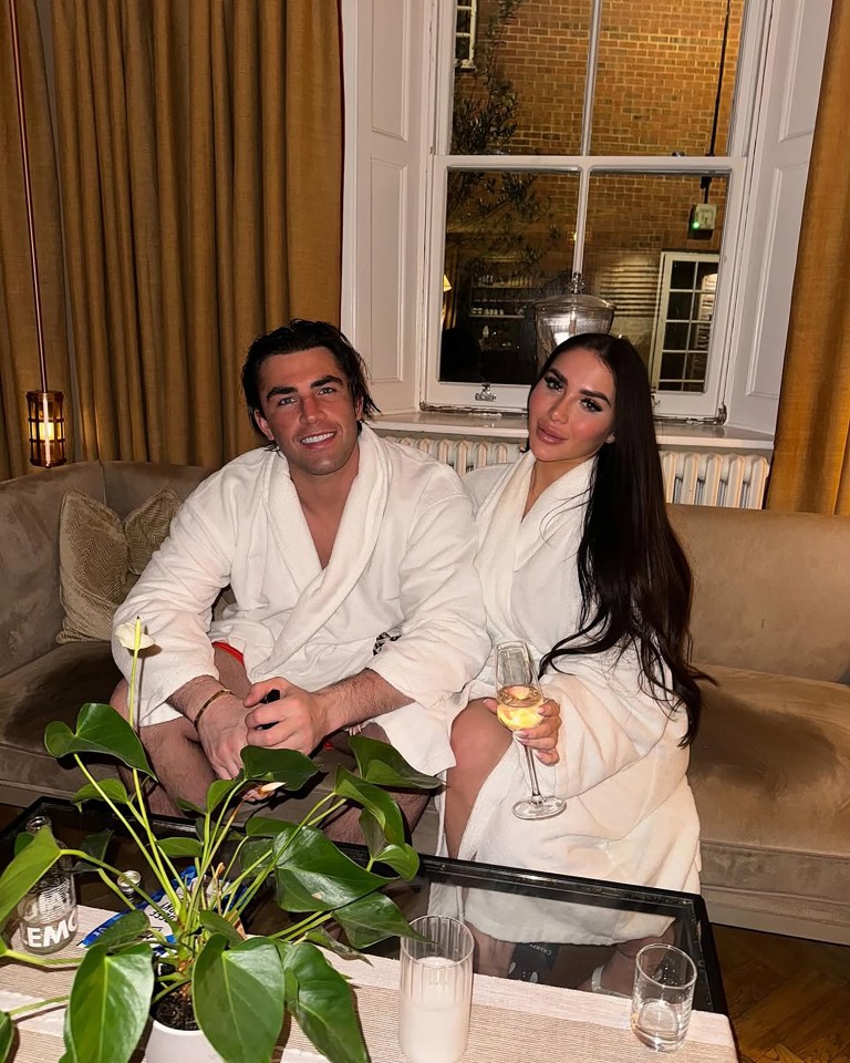Jack Fincham and Chloe Brockett in bathrobes, enjoying champagne.