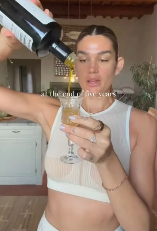 Woman pouring olive oil into a glass.