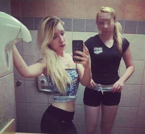 Photo of two young women in a restroom taking a selfie.